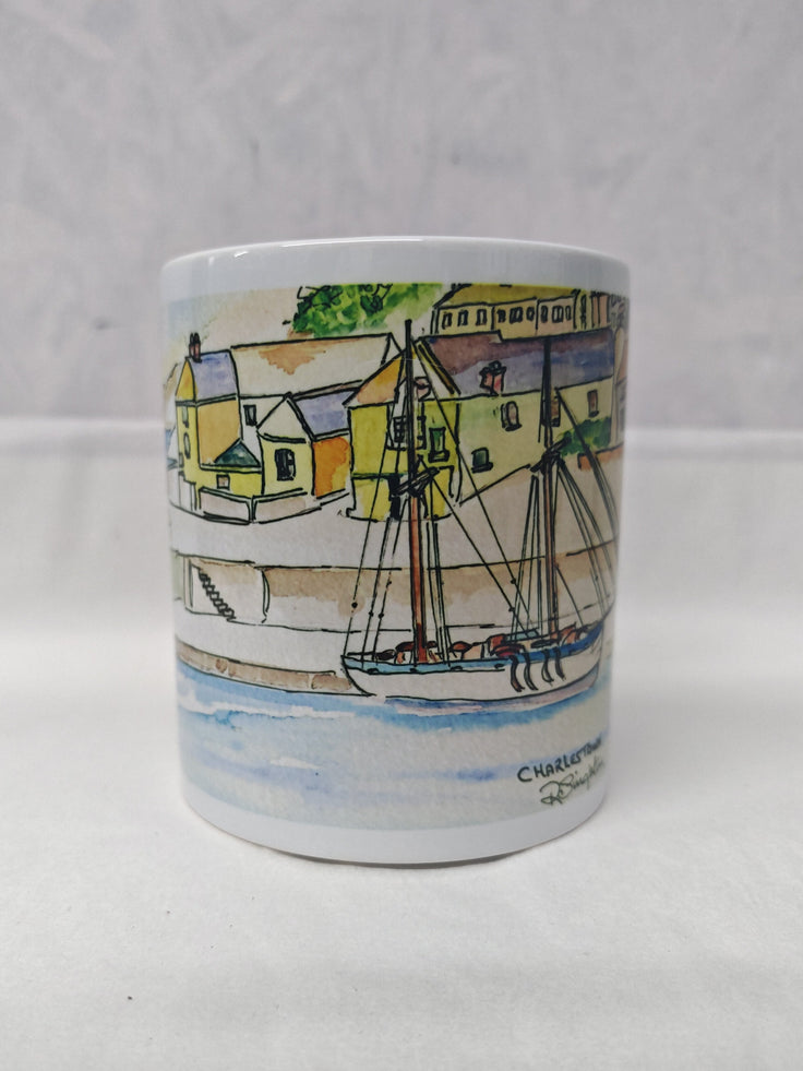 A white ceramic mug featuring Charlestown harbour in cornwall, a watercolour painting from R Singleton and reproduced onto accessories such as mugs, coasters and magnets by HLSdesigner in cornwall. This is an image of the side of the mug with the full wrap around image printed and focuses on the fishing village over looking the tail ships in the harbour, painted with colour washes and linear detailing enhancing the negative space to create a modern look. 