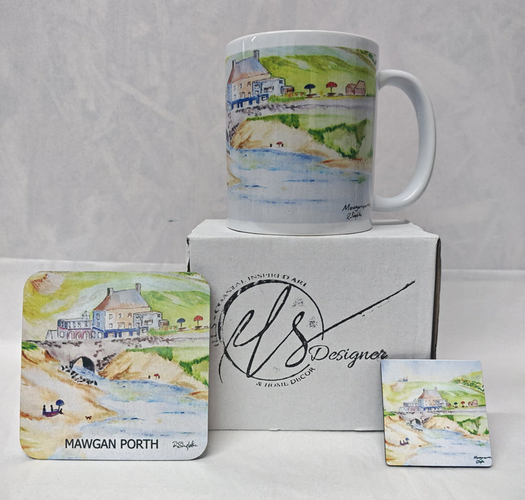 A white ceramic mug with a watercolour coastal scene stands on top of a white box, with matching printed coasters displayed in front. The box and coasters show the brand name 'HLS Designer' and the location 'Mawgan Porth'. Painted in watercolour by R Singleton and reproduced by his daughter Hannah in tribute. In the collection is a mug, a coaster and a magnet as well as available fine art prints reproduced from his original Cornwall paintings