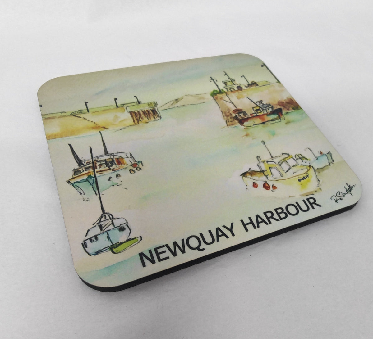 A square coaster with rounded corners featuring a watercolor painting of fishing boats in Newquay Harbour, with the text 'NEWQUAY HARBOUR' printed along the bottom edge. Painted by R Singleton and printed exclusively by HLSdesigner