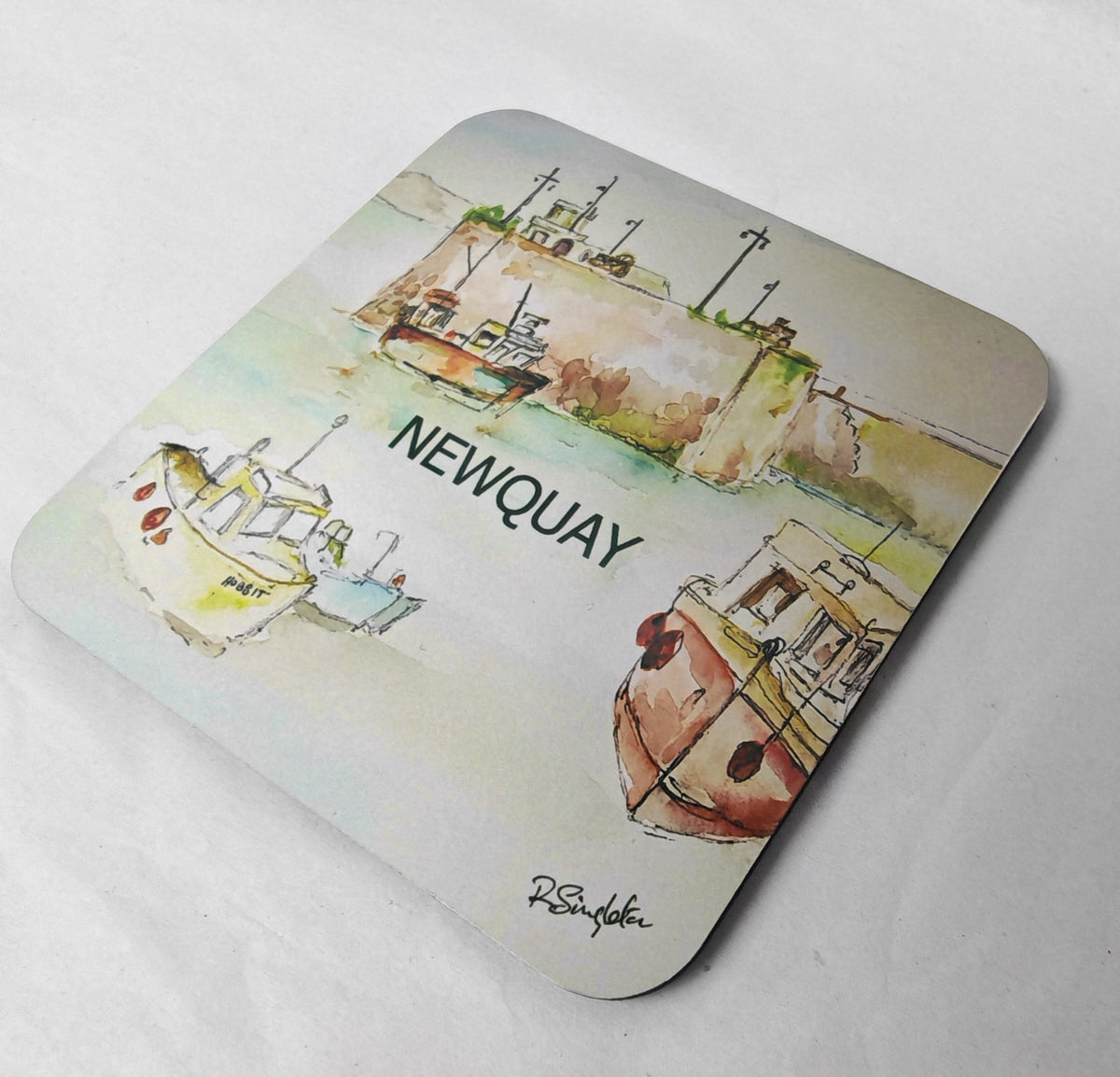 A square coaster with rounded corners featuring a watercolour painting in a modern style by R Singleton of Newquay harbour in cornwall