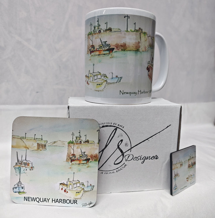 A Newquay Harbour themed gift set featuring a white ceramic mug, a square coaster, a small square wooden magnet to match and a branded HLSdesigner white box. The items are decorated with a watercolour painting of fishing boats on a harbour and the text 'Newquay Harbour' and 'Newquay Bay'.