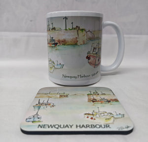 A white ceramic mug and matching rectangular coaster featuring a watercolour illustration of Newquay Harbour with boats and the text 'Newquay Harbour' and 'NEWQUAY HARBOUR'. HLSdesigner