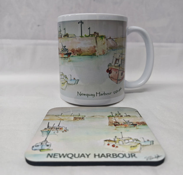 A white ceramic mug and matching rectangular coaster featuring a watercolour illustration of Newquay Harbour with boats and the text 'Newquay Harbour' and 'NEWQUAY HARBOUR'. HLSdesigner