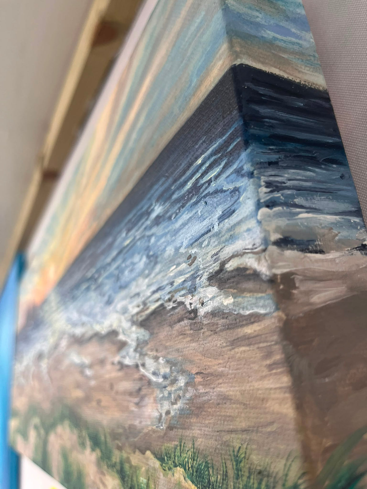 A close up painting texture of an original artwork by Hannah Singleton, Local known ocean artist from Cornwall. Abstract expressionist brush strokes and paint bleeds finish this piece off to a beautiful representation of the ocean flooding into the shoreline at Holywell Beach, Photo taken from the side of the deep set canvas showcasing the beautiful finish to the painting. Find more at HLSdesigner