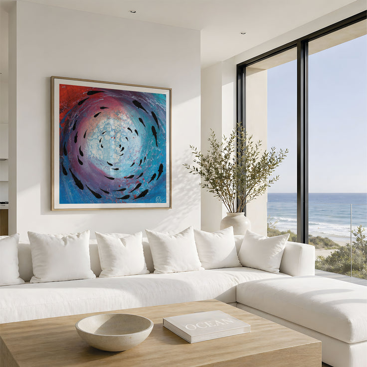 A framed abstract painting featuring a swirling vortex of blue, purple, and red with black fish-like shapes, displayed on a white wall above a modern white sectional sofa in a bright coastal living room.This is fish shoal 8 - a abstract collection of 12 pints featuring shoaling fish s you look up toward the surface. Designed by Hannah Singleton at HLSdesigner, coastal inspired art inspired by the ocean viewpoints.