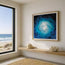 Image of a reception area with decorative shells on a shelf and a painting framed hanging above it, this is fish shoal 7, a depiction of fish shoaling through the ocean in an abstract form. To the left is a beach view through a patio window creating a beach house themed look. Print not to scale. Image for display only. Designed by Hannah Singleton, HLSdesigner, Coastal ocean inspired Cornwall artist