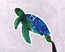 green and blue sea turtle illustration made into a die cut vinyl sticker held by tweezers against a white background