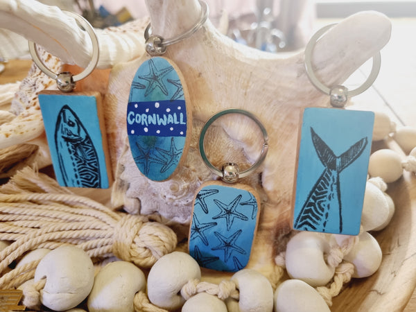 Set of blue keychains with ocean-themed designs on a shell and seashell background, hand painted by HLSdesigner 