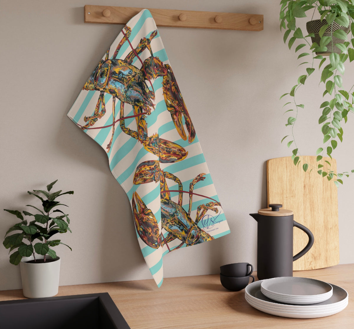 Colorful towel with nature-themed lobster design with a nautical striped background, hanging on a wooden rack in a kitchen setting.
