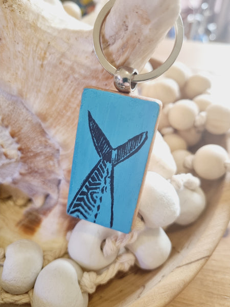 hand painted mackerel tail keyring in an Aztec inspired style in black with a blue background surrounded with handmade garlands and seashells by HLSdesigner