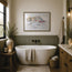 A framed watercolor painting of a harbor scene hangs on a beige wall above a white freestanding bathtub in a styled bathroom with wood wainscoting, a window, candles, towels, and a vanity. The picture in the frame is a reproduction print of an original watercolour painting by Robert singleton and produced exclusively by HLSdesigner - this is a print featuring mevagissey - a beautiful coastal town in the heart of Cornwall 