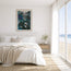 A framed abstract art print featuring deep teal, black, and blue tones, displayed on a white wall above a neatly made bed in a bright, modern beach-view bedroom. Featuring beautiful forest greens and turquoise, focusing on shading and highlights to build layers that create the rippling waves and the reflections where the light hits the surface of the ocean. Designed and originally painted by Hannah Singleton ocean inspired fine artist from Cornwall