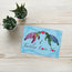 Card with two turtles and hearts on a wooden surface with plants reading ' I turtley love you'