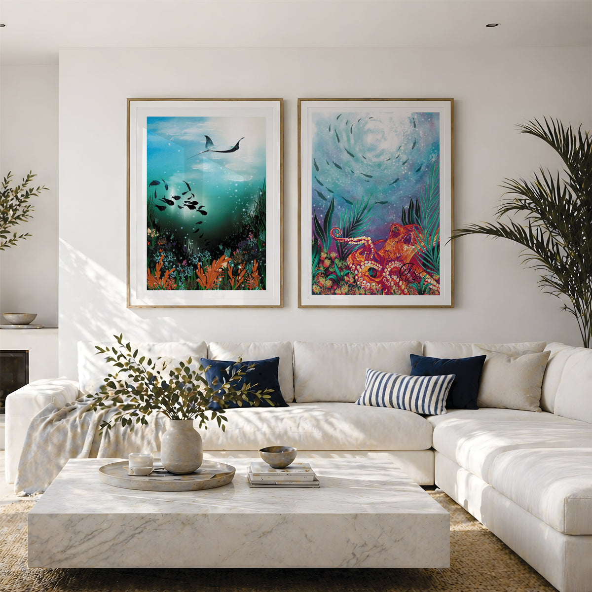 Two framed vertical underwater art prints hang side-by-side on a white wall above a modern white sectional sofa in a bright, contemporary living room. This is Octopi corals and Sun Rays - two fine art prints of digital illustrations created and designed by HLSdesigner Hannah Singleton, contemporary fine artist and illustrator from Cornwall inspired by the ocean. featuring cool greens and turquoise, fish shoaling around in the ocean and a sea creature taking focus in the painting. both have coral reefs