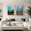 Two framed vertical underwater art prints hang side-by-side on a white wall above a modern white sectional sofa in a bright, contemporary living room. This is Octopi corals and Sun Rays - two fine art prints of digital illustrations created and designed by HLSdesigner Hannah Singleton, contemporary fine artist and illustrator from Cornwall inspired by the ocean. featuring cool greens and turquoise, fish shoaling around in the ocean and a sea creature taking focus in the painting. both have coral reefs
