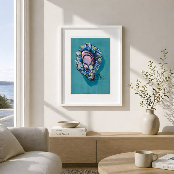 A framed art print featuring a colorful abalone shell illustration on a teal background, displayed on a beige wall in a modern, sunlit living room setting. This is a gouache painting to represent a colourful and vibrant king oyster featuring Lemon yellow hues paired lovingly with oyster blue and lilac shading to create a 3d effect. Painted and reproduced into prints by artist Hannah Singleton, ocean inspired illustrator and seafood artist from cornwall at HLSdesigner