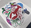 Colourful sticker with a lobster design on a white tray and a selection of die cut stickers, vinyl waterproof stickers in a range of ocean creatures designed by HLSdesigner, from pink turtles, green turtles, squids, sardines, lobsters and starfish 