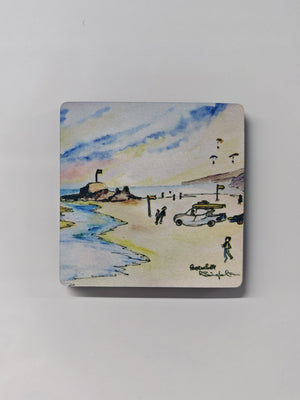 a square magnet with rounded edges with a gloss coating  finish, featuring a print of the watercolour perranporth painting by R Singleton, coastal cornish scenes ready to collect, a pretty depiction with a lifeguard vehicle on the sand, paragliding and beach goers showcasing the cornish flag on the perran rock as the tide comes in.