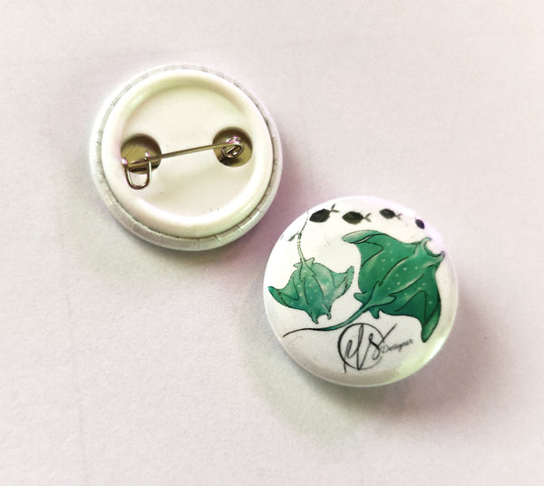 Button badge with greeny blue manta rays design on a white background