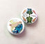 Two button pin badges with turtle designs on a light background with lost at sea message in a bottle illustration