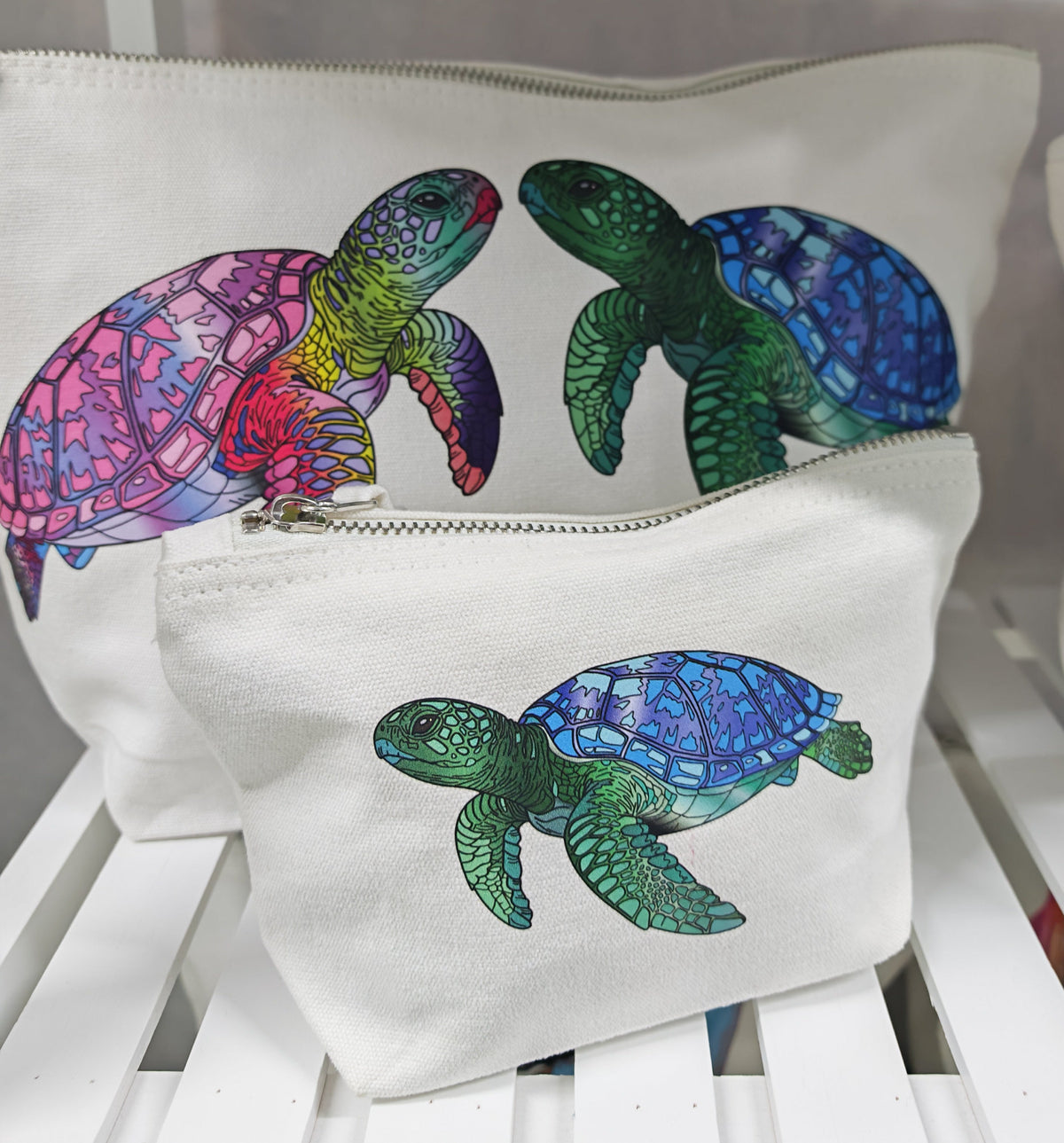 showing the large and the small accessory bag sizes, these showcase the pink and green turtles facing each other and the small bag has a single green turtle illustration pressed onto it 