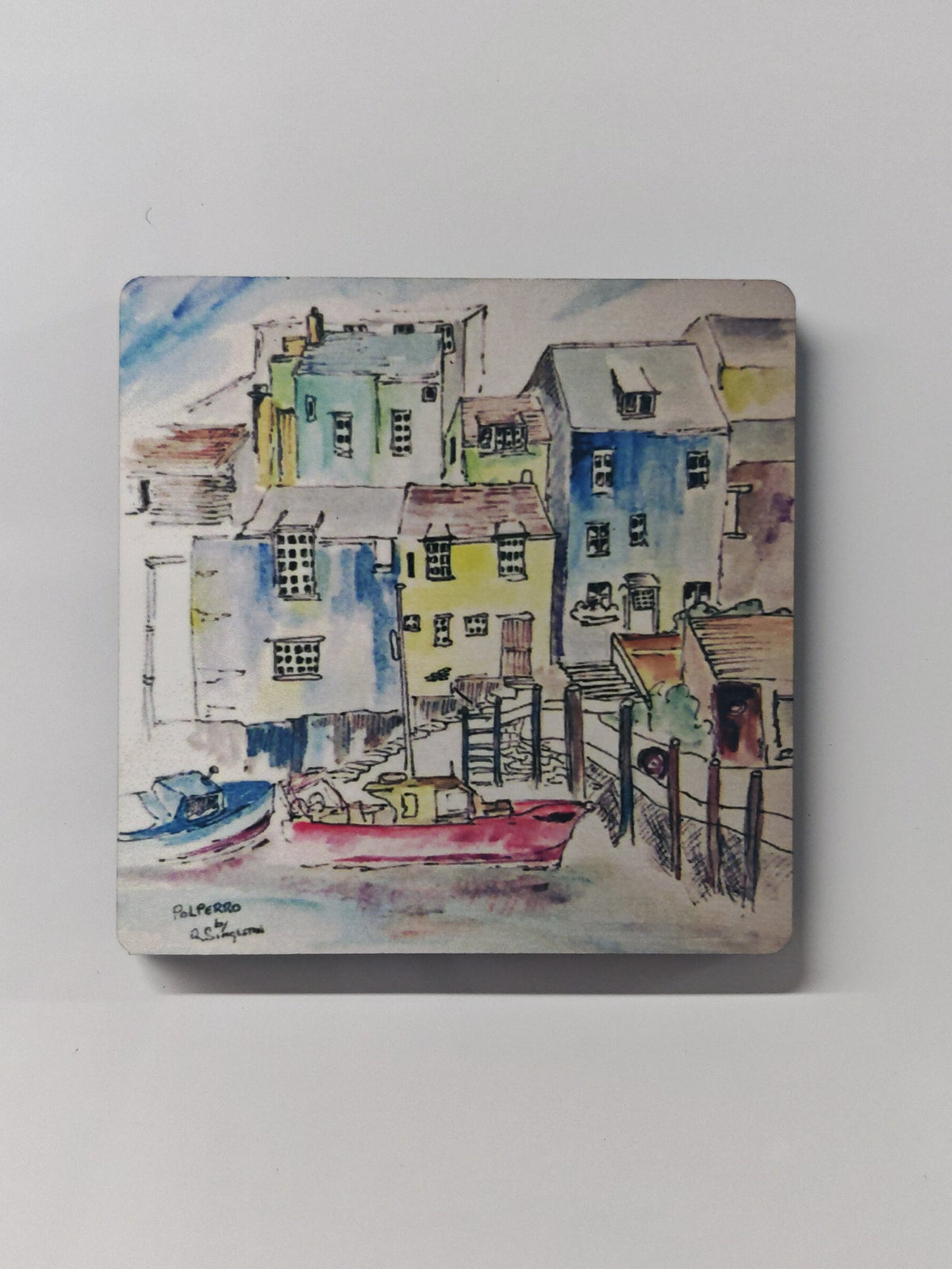 a square wooden fridge magnet with a high gloss finish and curved corners, watercolour painting by R Singleton of Polperro boats also available as a fine art print, this is a magnet gift souvenir from Cornwall and is reproduced exclusively by HLSdesigner in tribute. using blush reds and vivid blue colour washes to highlight the shadows of each house in the village, detailing with a fine linear technique and utilising negative space to create a modern feel. 