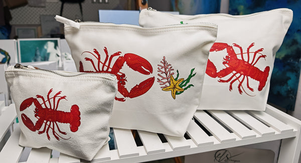 red lobster illustration by hlsdesigner printed and pressed in house onto beautiful cosmetic accessory bags, this one features the set of three sizes in the lobster design side on close up on a white shelf and is complete with a silver metal zip.