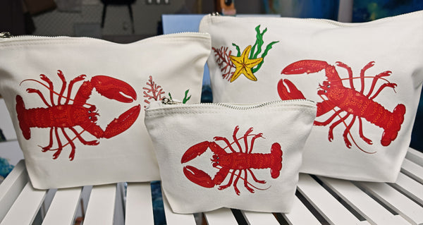 red lobster illustration by hlsdesigner printed and pressed in house onto beautiful cosmetic accessory bags, this one features the set of three sizes in the lobster design side on close up on a white shelf and is complete with a silver metal zip.