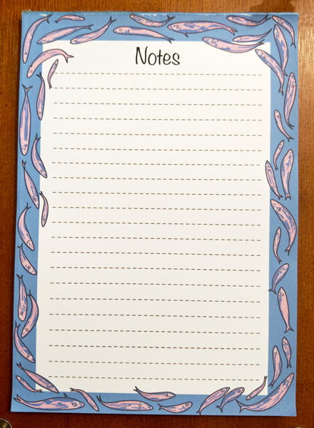 fish shoal 50 page tear off notepad designed by HLSdesigner on heavy duty paper with a card backing. Incorporating lovingly drawn sardines in pinks and purples with a deep blue background around the outer side of the pages with a dotted lined inside for notetaking