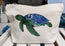 this image shows the smaller sized accessory bag with a single green and blue turtle illustration pressed onto the front of the bag