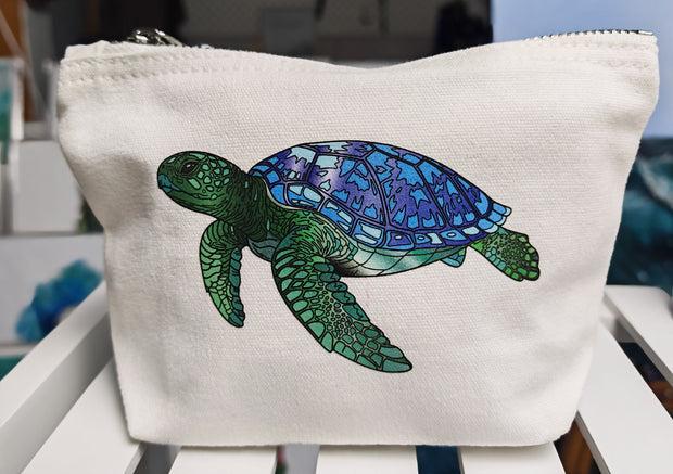this image shows the smaller sized accessory bag with a single green and blue turtle illustration pressed onto the front of the bag