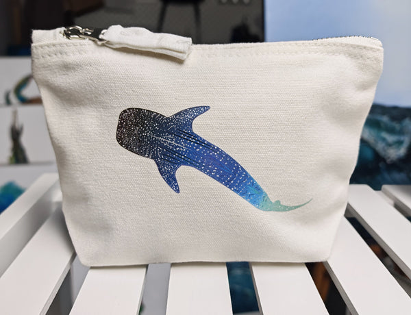 small whale shark cosmetic bag, off white cotton canvas accessory bag with metal zip, with ocean themed artwork in the background. whale shark illustration fading from blue to green with white spots pressed onto the bag