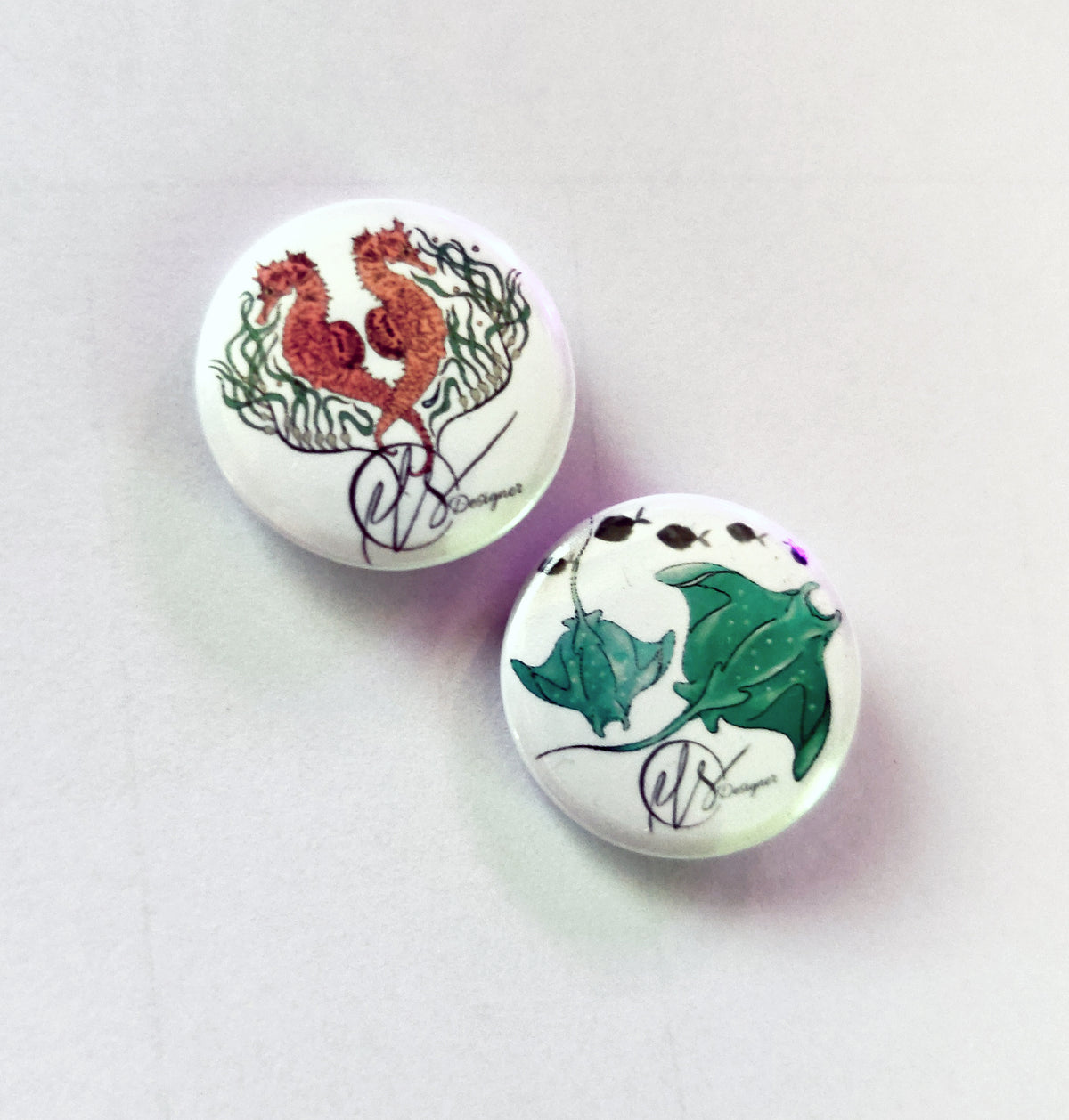 two handmade pin badges with seahorses from the seahorse trident series and two manta rays on the badge available in a set of two. handmade and designed by HLSdesigner