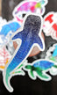 whale shark illustrated die cut sticker raised above a variation of other ocean creature stickers in the background by HLSdesigner