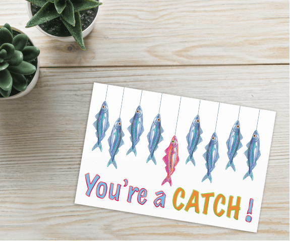 nautical sardine catch of the day greetings card, reading 'you're a catch' with blue sardines surround a pink sardine, hand illustrated by HLSdesigner and made in house