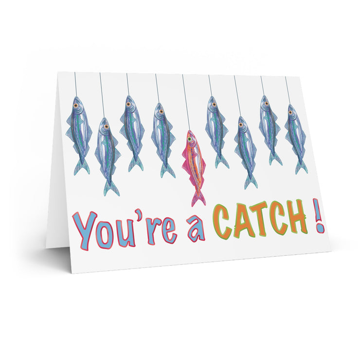 nautical sardine catch of the day greetings card, reading 'you're a catch' with blue sardines surround a pink sardine, hand illustrated by HLSdesigner and made in house